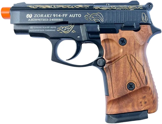 A Zoraki 914-FF Auto toy pistol with a black metal slide featuring gold engravings, a brown wood-grain textured grip, and an orange safety tip, shown against a plain white background.