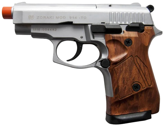 A Zoraki Mod 914 TD semi-automatic pistol with a silver metallic slide and a brown wood-grain textured grip, featuring an orange safety tip and black accents.
