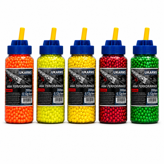 Five UKARMS high performance airsoft pellets in clear plastic bottles with blue caps and yellow nozzles, shown in orange, yellow, gold, red, and green colors on a white background.